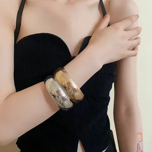 Dettaglio di bracciali rigidi metallici oro e argento con trama a pelle di coccodrillo