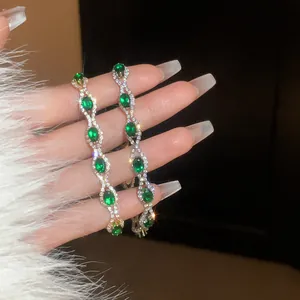 Close-up of elegant silver-tone bracelets featuring sparkling green oval crystals.
