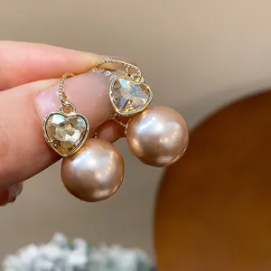 Gros plan de boucles d'oreilles élégantes cœur en cristal et perle rose, style français.