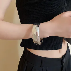 Primo piano di un bracciale rigido in metallo argento lucido indossato sul polso