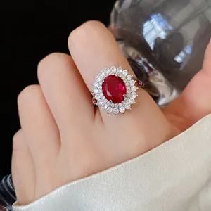 Close-up of a luxury silver open ring with a large oval red zircon and diamond halo detail.
