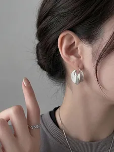 Stylish silver brushed metal geometric hoop earrings shown clearly on a model's ear