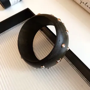 Detailed view of chunky dark green acrylic bracelet with silver star and stud motifs