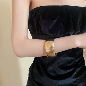 Dettaglio di un ampio bracciale a polsino in metallo dorato martellato indossato