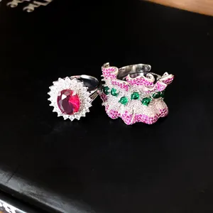 Detail of an irregular pleated ring with pink pavé stones and a halo red gem ring