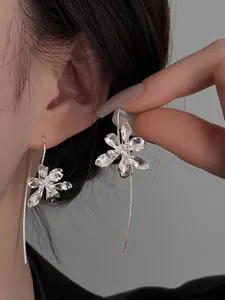 Detailed macro shot of elegant silver flower drop earrings with a brushed metal finish.