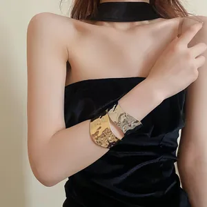 Primo piano di ampi bracciali a polsino martellati in oro e argento su modella
