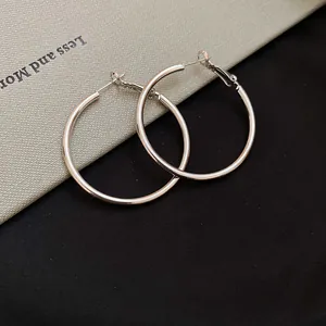 Detailed macro view of minimalist large silver hoop earrings with a polished metallic finish