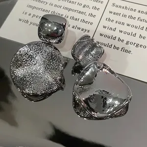 Detailed macro view of silver geometric stud earrings with brushed and mirror finishes