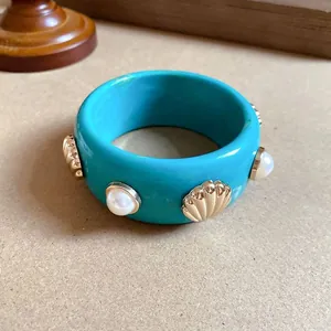 Vista dettagliata del bracciale in resina turchese con conchiglie dorate e accenti di perle