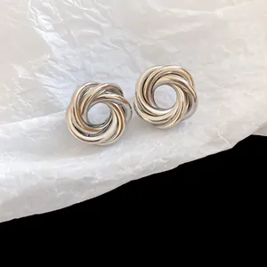 Detailed close-up view of silver-colored interlocking metallic stud earrings with a woven design