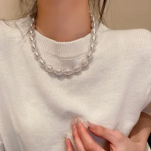 Detailed shot of a baroque pearl necklace with textured ribbing on a white sweater