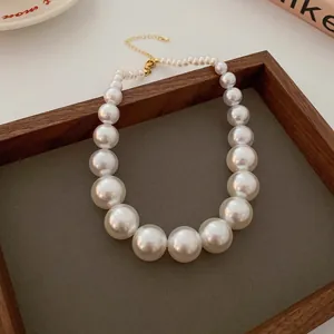Detailed view of graduated faux pearl necklace with gold-tone lobster clasp.