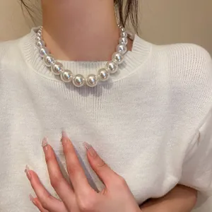 Detail view of a vintage graduated pearl necklace worn with a white knit sweater.