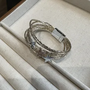 Vista dettagliata di un bracciale multistrato argento con tre ciondoli a stella decorativi.