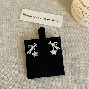 Close-up detail showing sparkling zircon bow and star stud earrings on a display stand.