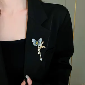 Détail d'une broche papillon à glands en zircon étincelant sur un blazer noir chic.