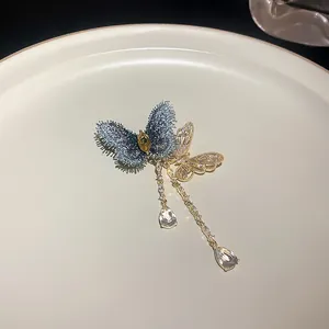 Vue détaillée d'une élégante broche double papillon avec glands en zircon sur une assiette.