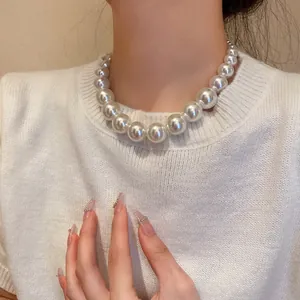 Detailed close-up of a vintage gradient pearl necklace worn on a white knit top