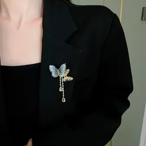 Vue détaillée d'une broche papillon avec broderie bleue et glands en cristal sur un blazer.