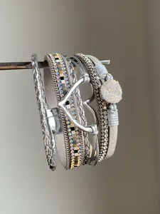 Dettaglio del bracciale multistrato grigio con strass e ciondolo a cuore color argento.
