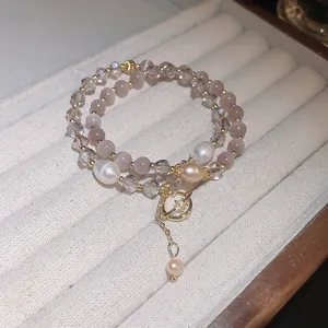 Detail view of a double-layered bracelet featuring cat eye stones and lustrous pearls.