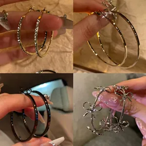 Detail view of four stylish metal hoop earrings in gold, silver, black, and bow designs