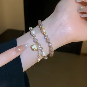 Detailed close-up view of cat eye stone and pearl double-layer bracelet on wrist.
