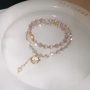 Close-up of double-layer bracelet with cat's eye stone, crystals, and pearl planet charm