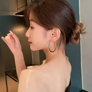 Side view of an elegant Asian woman wearing large two-tone metallic hoop earrings.