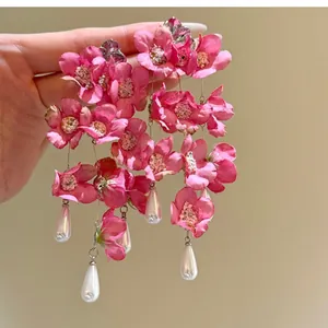 Gedetailleerd aanzicht van roze stoffen bloemenoorbellen met elegante witte druppelvormige parels