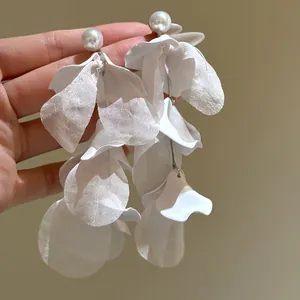 Gedetailleerd beeld van witte stoffen bloemblad oorbellen met parelknopjes voor dames.