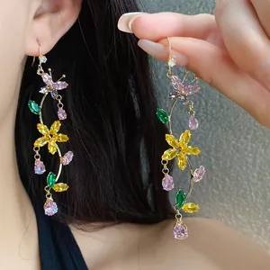 Detailed view of colorful zircon butterfly and flower drop earrings worn by a model.