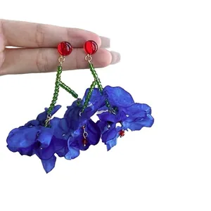 Vibrant blue fabric flower tassel earrings with red and green bead details.