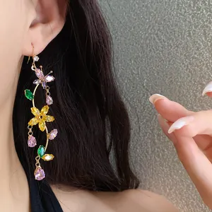 Close-up detail of elegant colorful zircon butterfly flower drop earrings worn by a model