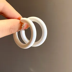Minimalist white chunky acrylic C-shaped hoop earrings shown held by hand for scale