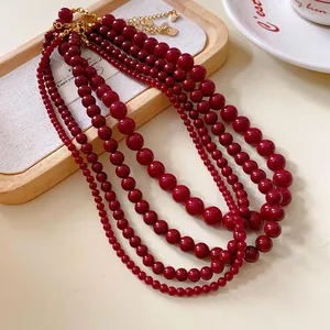 Detailansicht der roten Glasperlenketten im Vintage-Stil auf einem hölzernen Schmucktablett