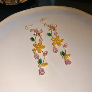 Macro view of glittering zircon butterfly and flower tassel earrings in gold