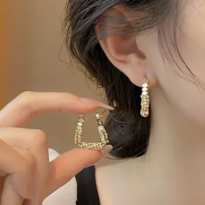 Dettaglio di eleganti orecchini a cerchio a forma di U placcati in oro con zirconi