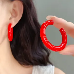 Detailed close-up view of bright red glossy acrylic C-shaped hoop earrings for women
