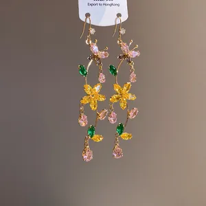 Detailed macro view of colorful zircon butterfly and flower dangle earrings on card