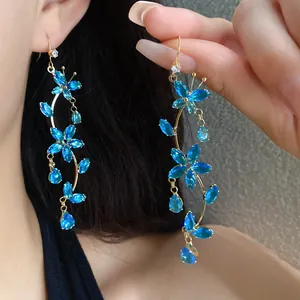 Detailed view of long blue zircon butterfly flower tassel earrings worn by a model.