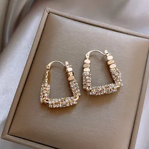 Dettaglio macro di orecchini a cerchio a forma di U placcati in oro con zirconi pavé