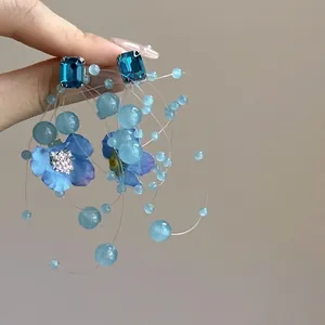 Macro shot showing detail of blue woven flower tassel earrings with faceted crystals