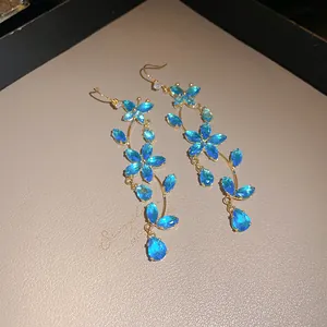 Detailed view of elegant blue zircon butterfly and flower dangle earrings with gold hooks