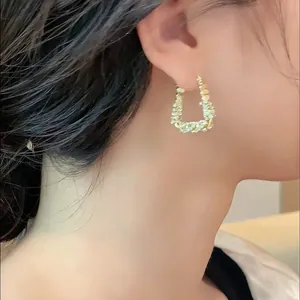 Dettaglio degli orecchini a cerchio a forma di U placcati in oro con zirconi da donna.