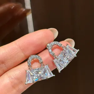 Detailed macro view of handbag-shaped silver stud earrings with sparkling crystals