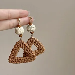 Detail view of handmade woven triangle earrings with natural wood and rope beads