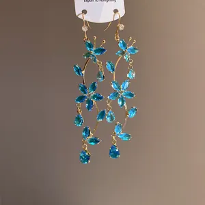 Close-up detail of elegant blue zircon butterfly and flower tassel earrings