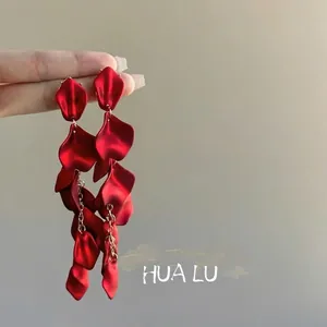 Detailed view of elegant long red petal tassel earrings with gold chains.
